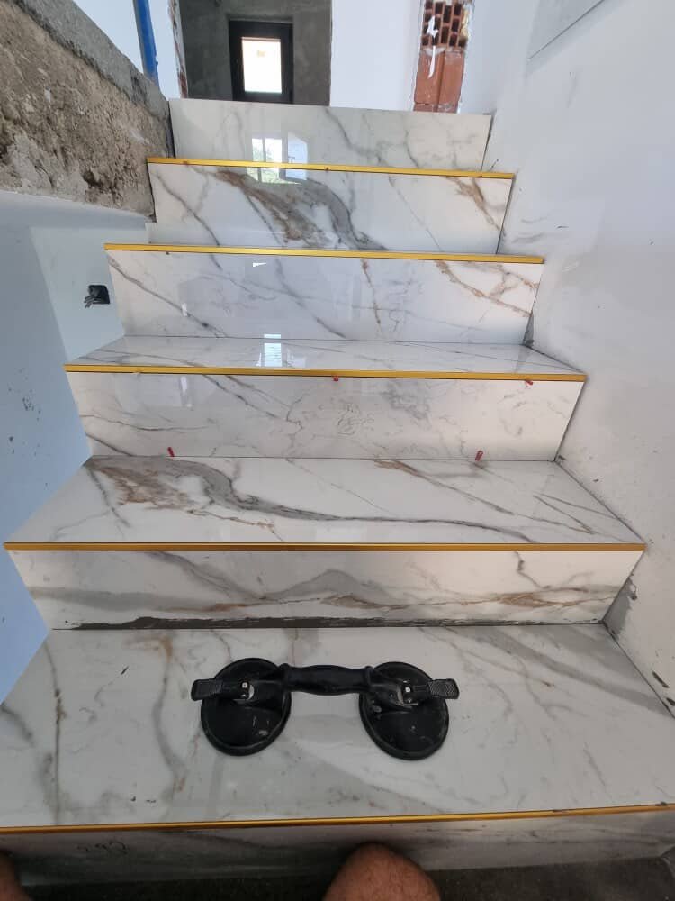 Detalj stepeništa sa belim pločicama i zlatnim lajsnama